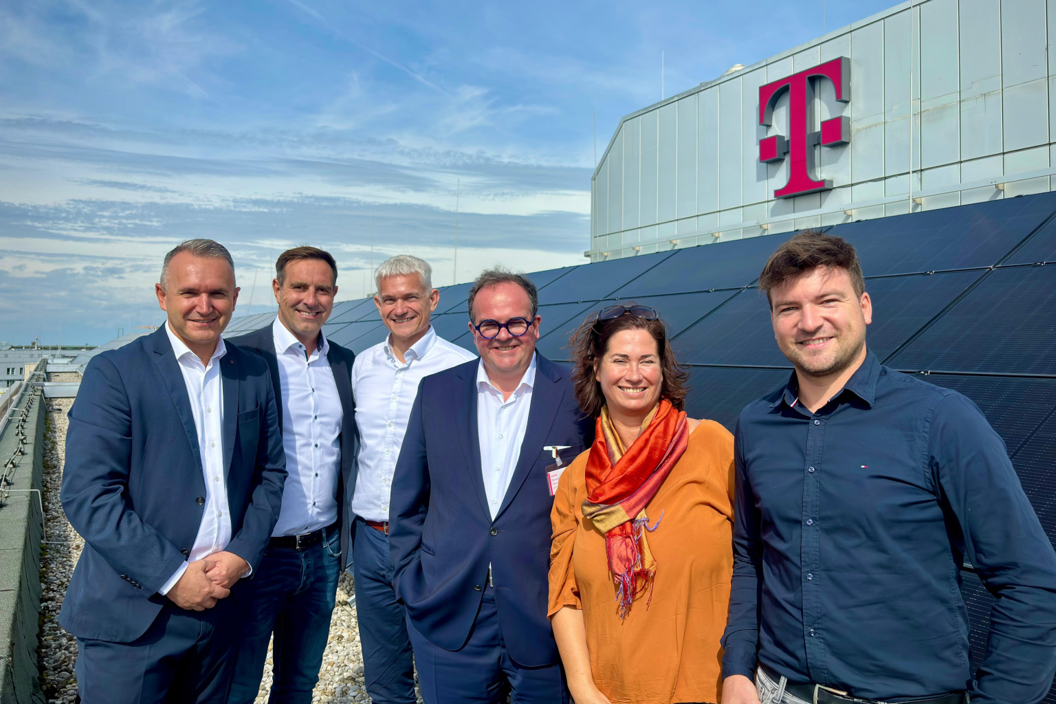 Telekom-MItarbeitende und Wirtschaftsreferent C. Baumgärtner vor PV-Anlage der Telekom am Marsplatz